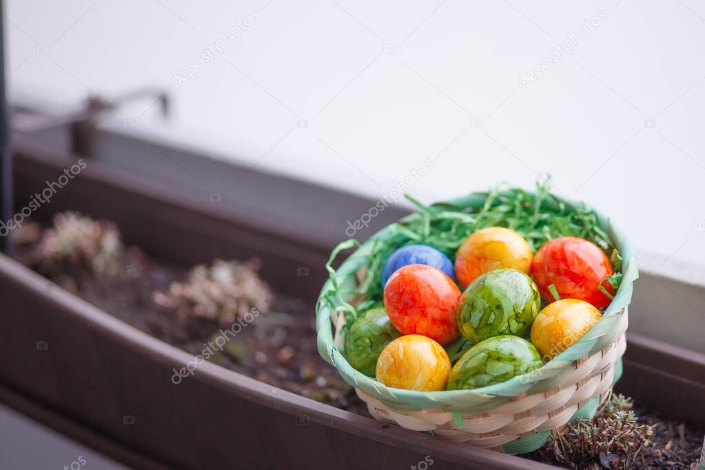Easter card. Flat lay composition with easter eggs in a basket on wooden background. Top view