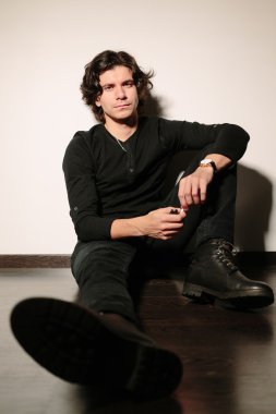 Katta ve duvara yaslanmış adam oturur.