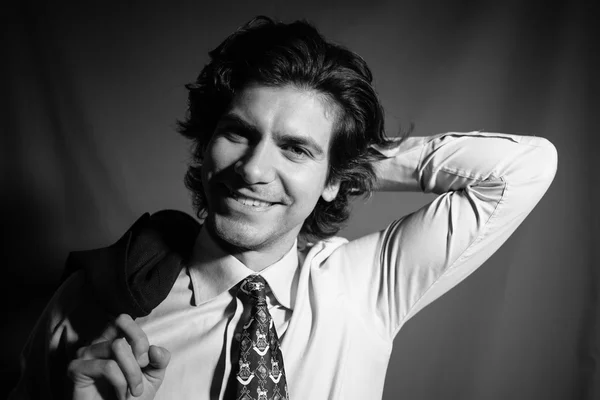 Молодой бизнесмен в рубашке с галстуком улыбается и держит пиджак за спиной . — стоковое фото