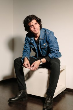 Genç adam bir sigara elinde tutan ve Osmanlı üzerinde oturur.