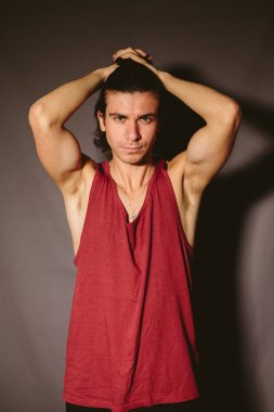 Kırmızı bir fanila ve ellerini başının arkasında bir sporcu genç adam.