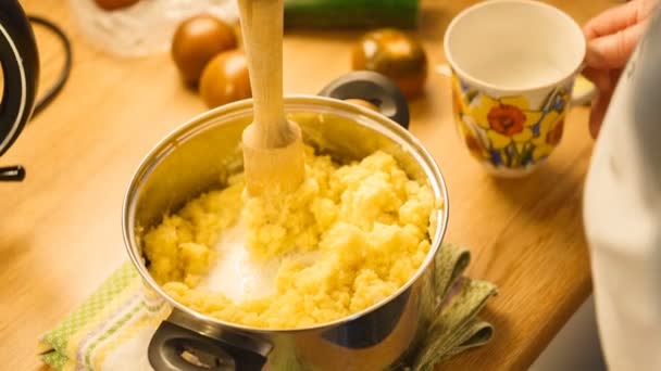 Verpletterende gekookte aardappelen met een aardappelstamper met de toevoeging van de melk. — Stockvideo