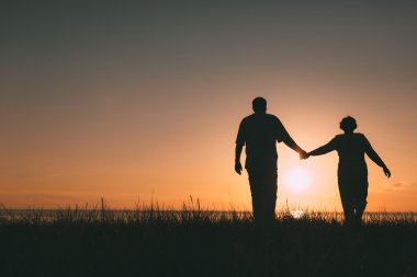 Gün batımında yetişkin çift siluetleri.