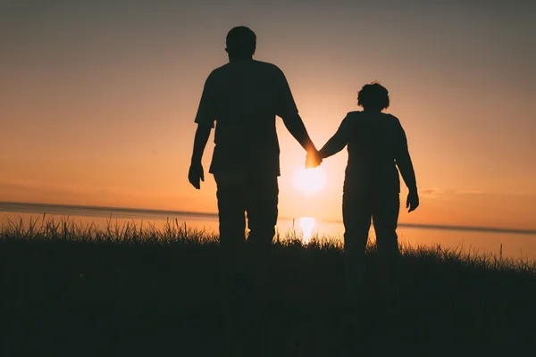 Silhouetten eines erwachsenen Paares bei Sonnenuntergang. — Stockfoto