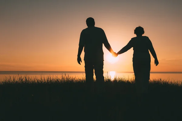 Volwassen paar silhouetten bij zonsondergang. — Stockfoto