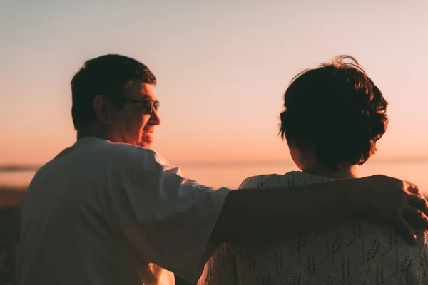 Rückseite ein Ehepaar eine Silhouette sitzt auf einer Bank. — Stockfoto