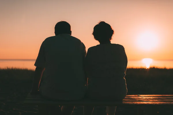 Rückseite ein Ehepaar eine Silhouette sitzt auf einer Bank. — Stockfoto