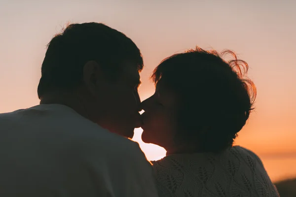 Доросла подружня пара цілується проти заходу сонця . — стокове фото