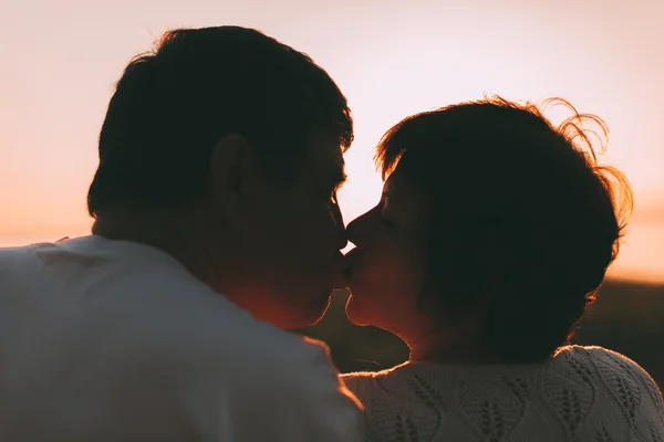 Yetişkin çift öpücük bir günbatımı karşı evli. — Stok fotoğraf