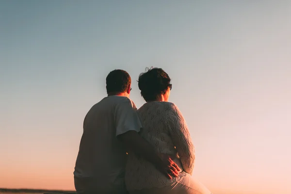 Volwassen paar omarmen bij zonsondergang en zee. — Stockfoto