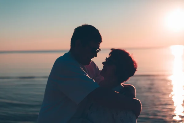 Gün batımı ve deniz kucaklayan yetişkin çift. — Stok fotoğraf