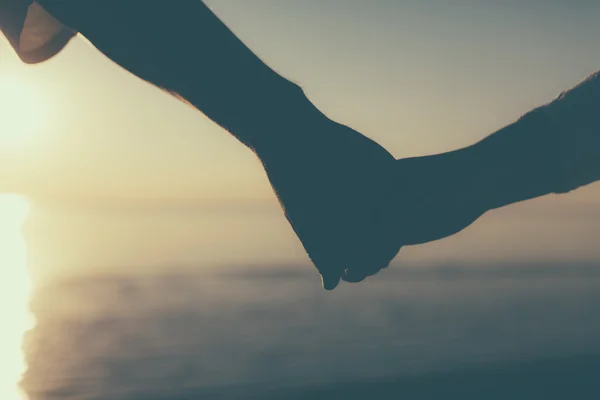 Paar Hände halten einander Silhouette auf einem Himmel und Meer Hintergrund. — Stockfoto