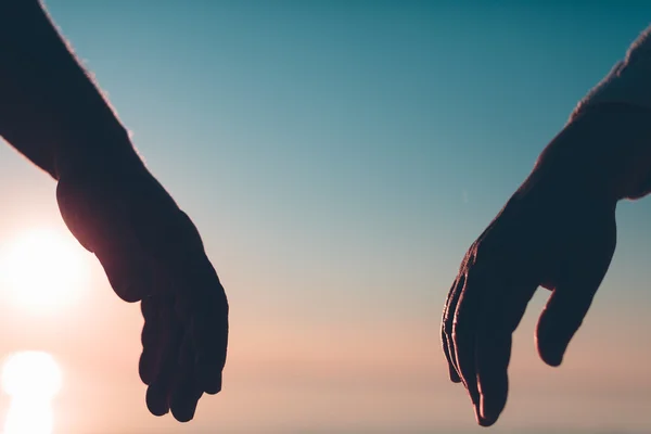 Пара рук достигают силуэта на фоне неба и моря . — стоковое фото