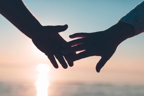 Paar Hände reichen Silhouette auf einem Himmel und Meer Hintergrund. — Stockfoto