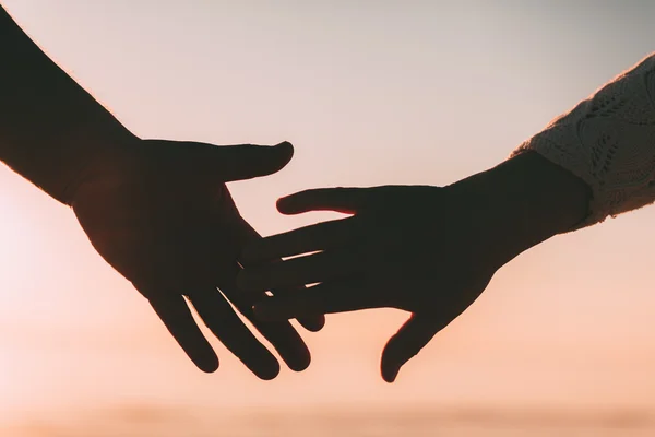 Пара рук достигают силуэта на фоне неба и моря . — стоковое фото