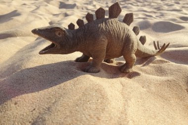 Oyuncak dinozor ayakta kum üzerinde şeklinde.