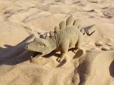 Oyuncak dinozor ayakta kum üzerinde şeklinde.