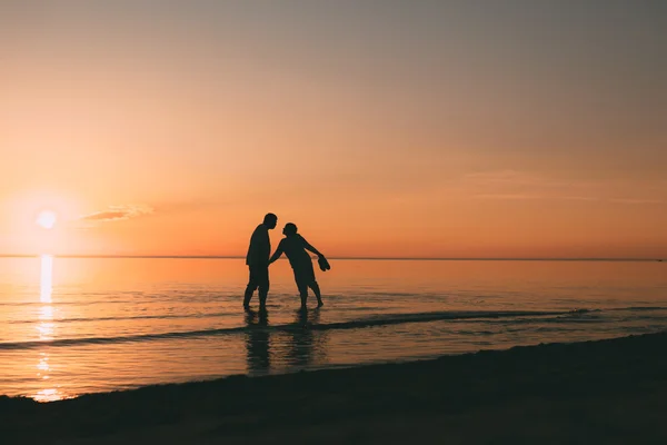 Silhouette eines im Wasser stehenden erwachsenen Paares will sich küssen. — Stockfoto