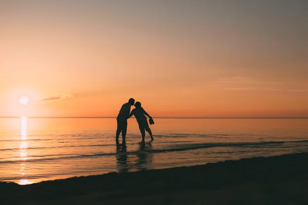 Silhouette eines im Wasser stehenden erwachsenen Paares will sich küssen. — Stockfoto