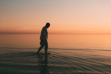 Yalnız adam denizde akşam yürür..