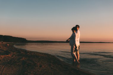 Yetişkin çift sahil üzerinde yürüyor.