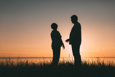 Gün batımında yetişkin çift siluetleri.