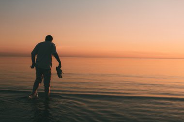 Yalnız adam denizde akşam yürür..