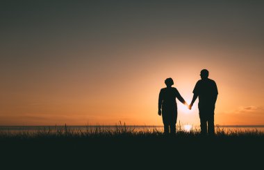 Gün batımında yetişkin çift siluetleri.