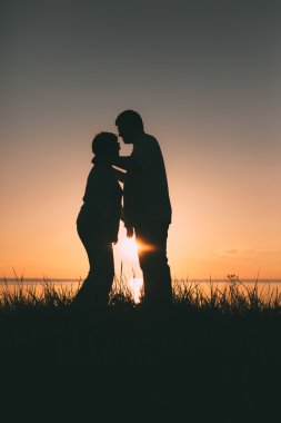 Gün batımında yetişkin çift siluetleri.