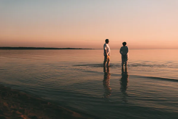 Sylwetka dorosłych para stoi na morzu przed zachodem słońca. — Zdjęcie stockowe