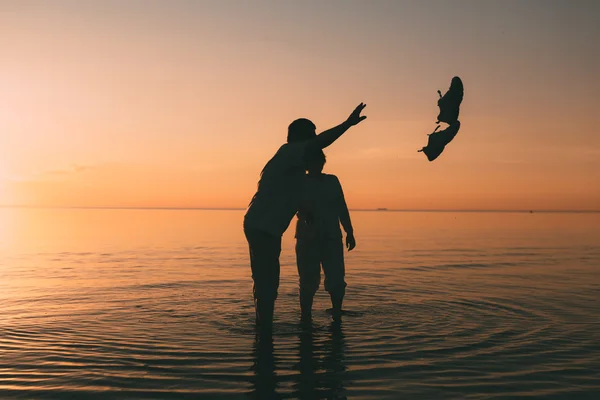 Mann und Frau stehen im Meer und werfen ihre Schuhe an den Strand. — Stockfoto