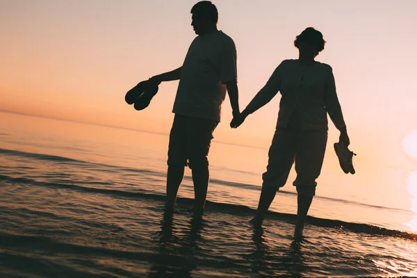 Silhouette eines erwachsenen Paares, das im Meer vor einem Sonnenuntergang steht. — Stockfoto