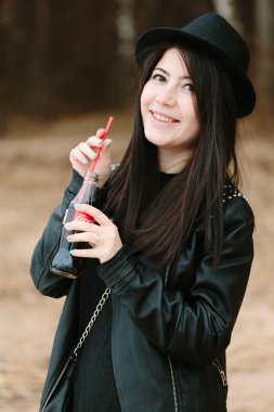 Siyah elbise ve siyah şapka coca cola içmek tutan genç yetişkin güzel esmer kadın.