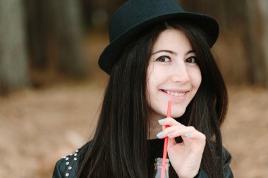 Güzel esmer kadın şapkası kırmızı pipet holding.