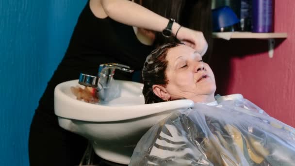 Friseur wäscht dem Kunden mit gefärbten Haaren den Kopf. — Stockvideo