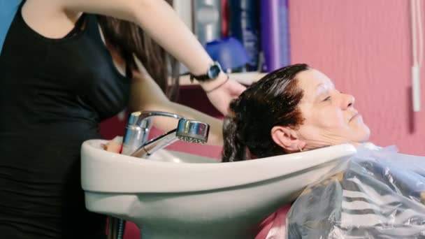 Kapper wassen hoofd naar de client met geverfd haar. — Stockvideo