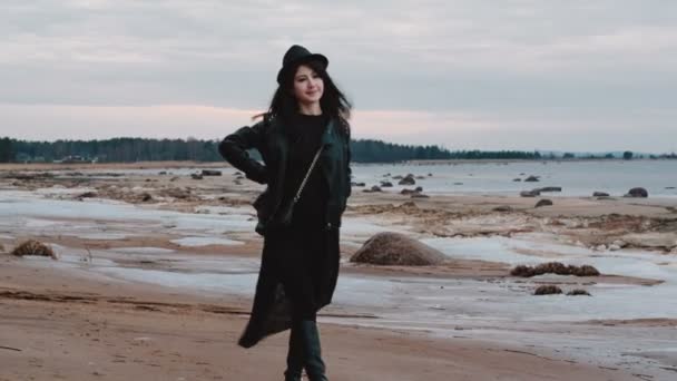 湾の岩の多い海岸を歩く黒ドレスの女の子. — ストック動画