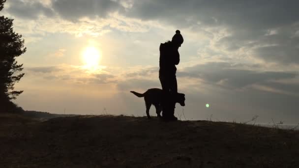 Sziluettjét a lány és a kutya ellen az égen és a nap. — Stock videók