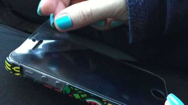 Los dedos femeninos con manicura quitan una película protectora del smartphone . — Vídeo de stock