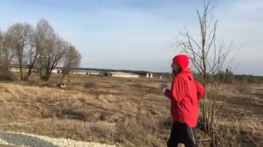 Sporcu kırmızı giysili kamera takip etsin park sokak üzerinde çalışır.