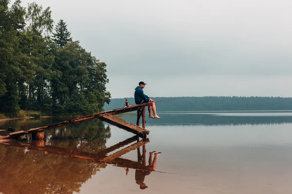 Omul stă pe un pod de lemn când peştele muşcă . — Fotografie, imagine de stoc