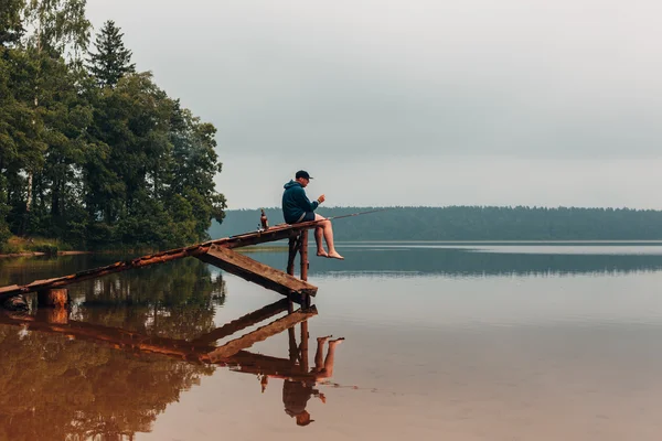 Omul stă pe un pod de lemn când peştele muşcă . — Fotografie, imagine de stoc