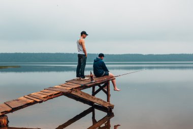 Ne zaman balık ısırma iki adam ahşap bir köprüde bekliyoruz.