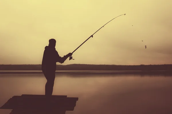 Mann wirft abends Angelrute in den See. — Stockfoto