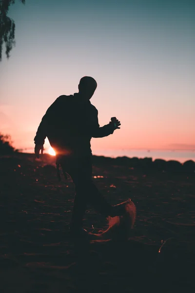 Silhouet van de persoon die in de hand drankje in een fles. — Stockfoto