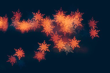 Karanlık bir arka plan üzerinde birçok turuncu kar taneleri.