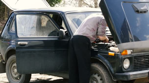 Man van gemiddelde jaar reparaties de auto. — Stockvideo