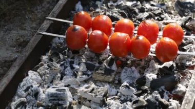 Domates kömürün üstünde yemek vardır.