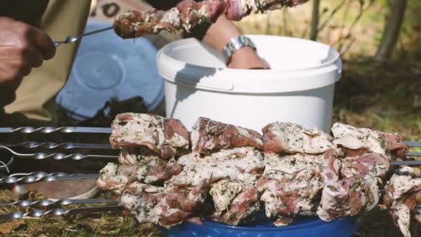 Людська рука накинула шматки м'яса на шампур . — стокове відео