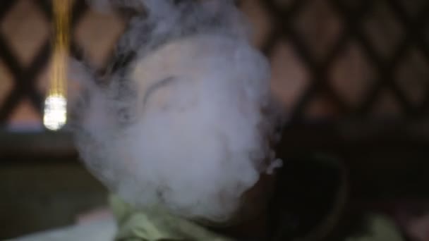 Young man lets out a smoke from a mouth and the camera pulls back. — Stock Video